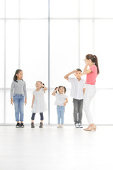 Naklejka premium Asian kids salute to Asian woman in pink shirt, she salute backto them, they stand in front of big white window.