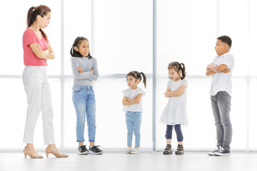 Asian woman in pink shirt and Asian boy and girls cross their one's arm, they stand in front of big white window.