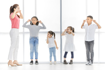 Fototapeta premium Asian woman in pink shirt and Asian boy and girls cross their one's arm, they stand in front of big white window.