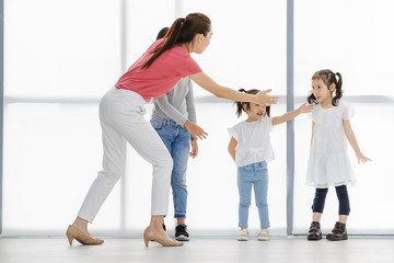 Asian woman in pink shirt and Asian kids stand and point at their tempura, they stand in front of big white window.