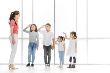 Fototapeta premium Asian woman and little Asian boy raise their one's hand among Asian kids in front of big white window.