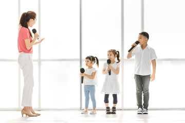 Teacher teaching group of kids to sing.