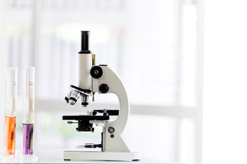 Colorful test tube and microscope on table in lab..