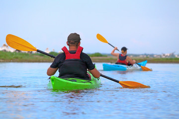 Man in kayak against the background of pelicans sitting on a sandy spit. Delta of Danube River near...
