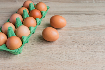 close up of raw brown chicken eggs in egg carton box on wooden table.