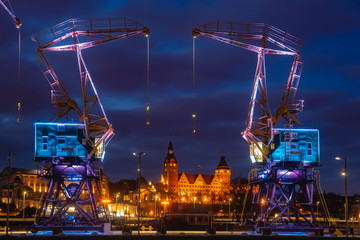 Illuminated old port cranes on a boulevard in Szczecin City at night - obrazy, fototapety, plakaty
