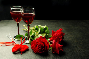 Two glasses of red wine, red roses and red hearts