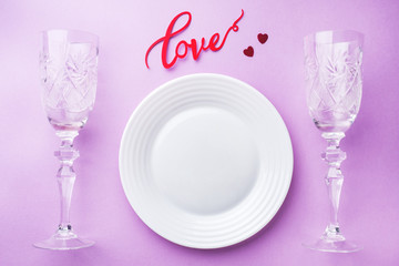 White plate, two glasses inscription love on a pink background. Concept Valentine's day.