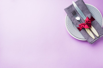 Cutlery, plates knife and fork with napkin on pink background. Holiday table concept