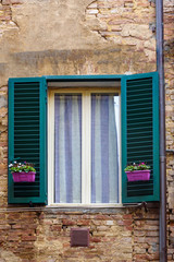 Fototapeta na wymiar Window with wooden shutters of old house in Siena. Italy