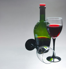 Two glasses of wine and a bottle on a light background