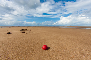 A red fishing net ball lies lonely on a tropical beach