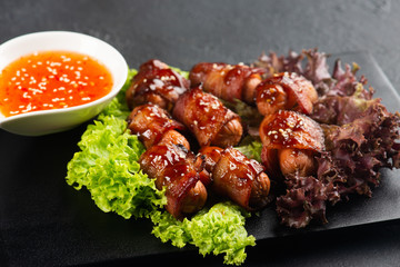 Pigs in blankets. Mini sausages wrapped in smoked bacon in baking dish