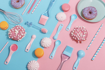 Kitchen utensils and tools, pastries and sweets on a pink and blue background. Top view. Copy space.