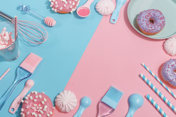 Kitchen utensils and tools, pastries and sweets on a pink and blue background. Top view. Copy space.