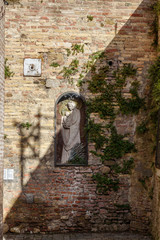 Old statue of madonna with child in wall on Fontegiusta street in Siena. Italy