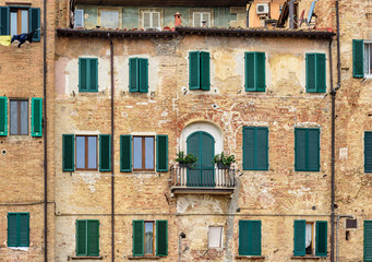 Old house with windows with wooden shutters in Siena. Italy