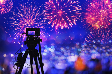 back side silhouette digital camera on tripod recording beautiful fireworks for celebrate in low light