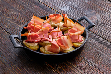 baked bacon with potatoes in a cast iron skillet