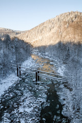 ice mountain river flows between winter hills, the bridge over the river