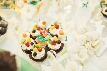 Delicious and tasty dessert table with cupcakes shots at reception closeup