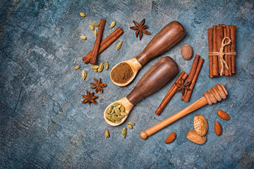 Top view on wooden spoons with mix of spices for traditional indian drink masala chai tea