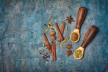 Top view on wooden spoons with mix of spices for traditional indian drink masala chai tea