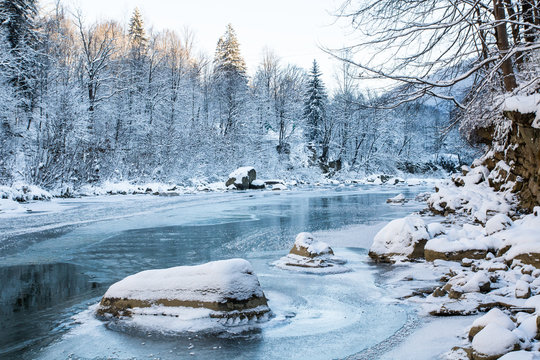scenic blue color frozen mountain river in spruce snowy forest
