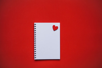 Empty notepad with heart on a red background. Festive concept of Valentine's Day or another love event in a minimal style.
