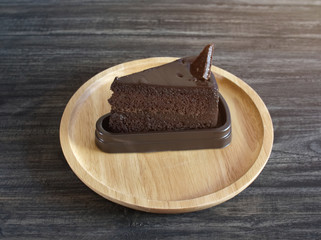 Dark chocolate cake one piece on wooden tray , vintage black table