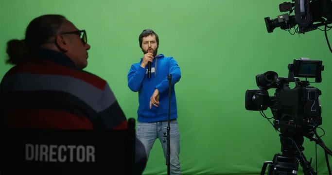 Medium shot of a director watching a man singing at an audition