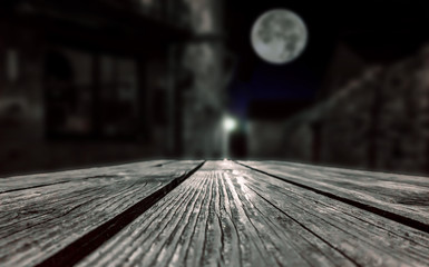 Empty surface of a wooden table in a village with a mysterious figure of a man at night