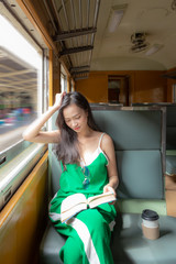 Fototapeta na wymiar A beautiful charming asian girl in casual dress concentrate reading a book. Gorgeous woman sit beside widow in retro train in morning. Feeling look happy and relax. Portrait lady on travel concept.