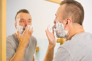 Guy shaving his beard in bathroom