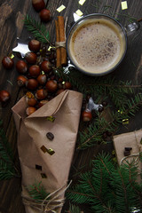 Hazelnut in craft paper with spruce twigs and coffee beans on a linen napkin. A cup of coffee with cinnamon. Christmas gift