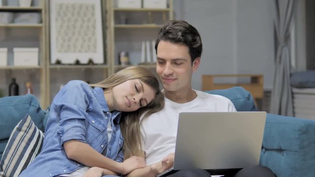 Happy Man Using Laptop while Sleeping Girlfriend Head on His Shoulder