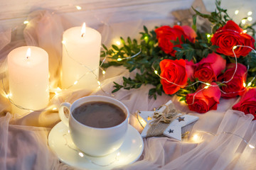Composition: red roses with boxwood, garlands, candles, star and cup coffee (tea)