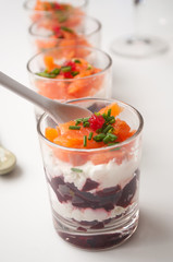 closeup of beet and salmon appetizers in little glasses on white background