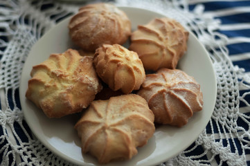 Homemade biscuits lies on a white plate. A plate with homemade cookies stands on a white knitted vintage napkin.