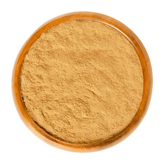 Cinnamon powder in wooden bowl. Spice from inner bark of the Ceylon cinnamon tree, Cinnamomum verum. Brown aromatic condiment and flavoring additive. Macro food photo closeup from above over white.