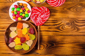 Different sweet candies on a wooden table. Top view