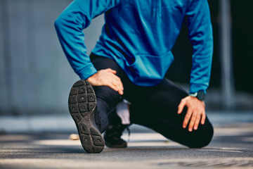 Close up of man stretching legs before running. Healthy lifestyle concept.