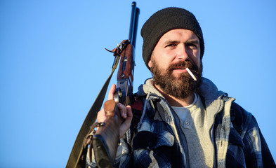 Man brutal bearded guy gamekeeper blue sky background. Brutality and masculinity. Hunter with rifle...