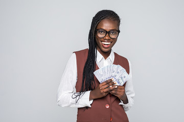 Portrait of excited african woman with afro hairstyle pointing finger on fan of money dollar bills...