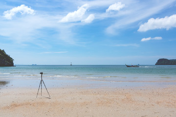 The camera stands on the beach of the tropical sea. The photographer's dream about his work. Soft focus.