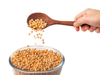 spoon in hand with yellow peas on white background. Peas in glass bowl