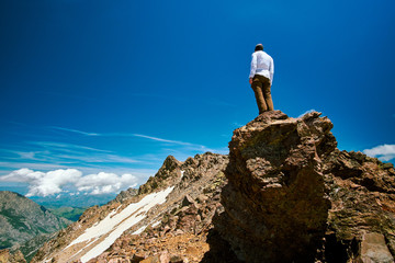 A tourist boy standing on top of the rock in high altitude under Monte Cinto Corsica Corse France on a sunny day GR20