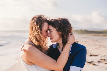Young couple in love hug each other on the deserted beach on a summer evening