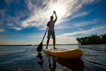 Happy man is paddling on a SUP board