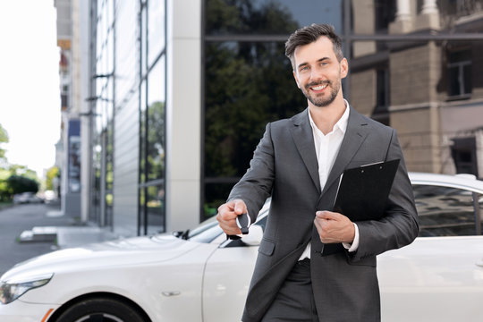 Man in suit holding out keys of new car
